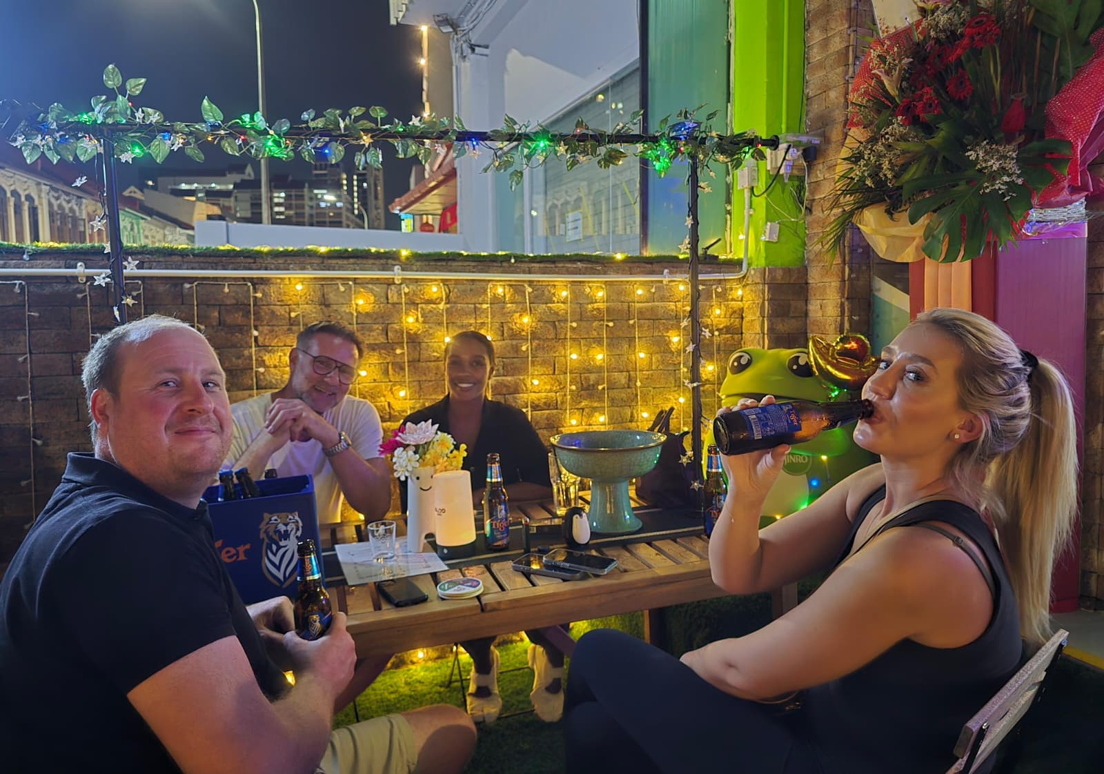 Four guests enjoying an evening at a garden table at Good Vibes Social Club